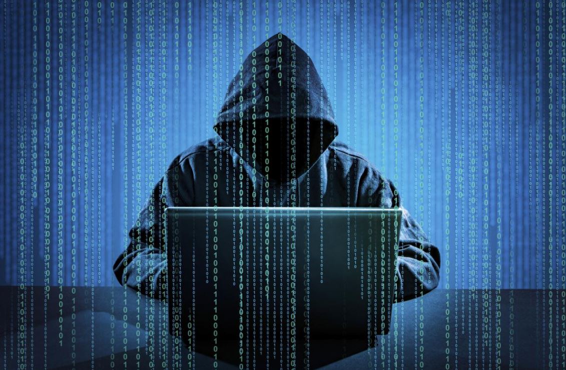 Man wearing a hood working from his laptop