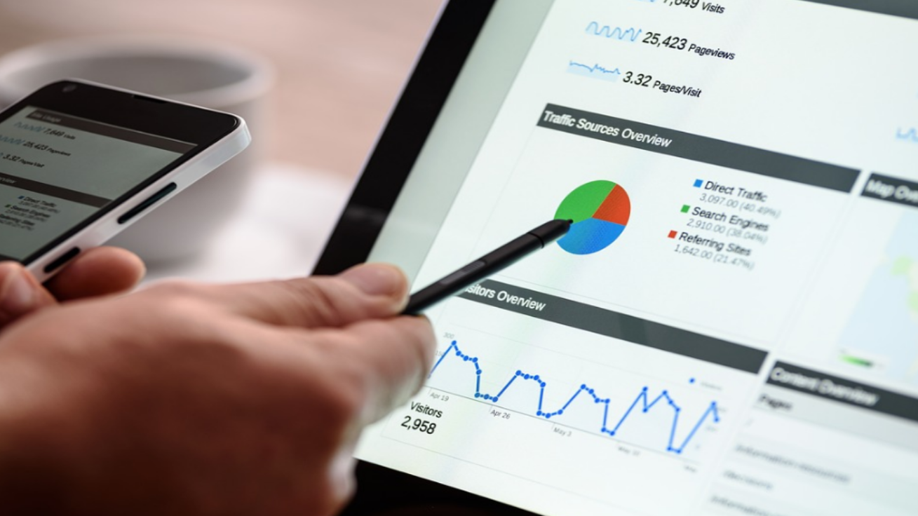 Hand holding a pen pointing to a pie graph